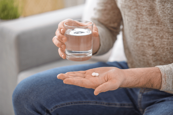 man taking pain medication to manage discomfort after jaw surgery